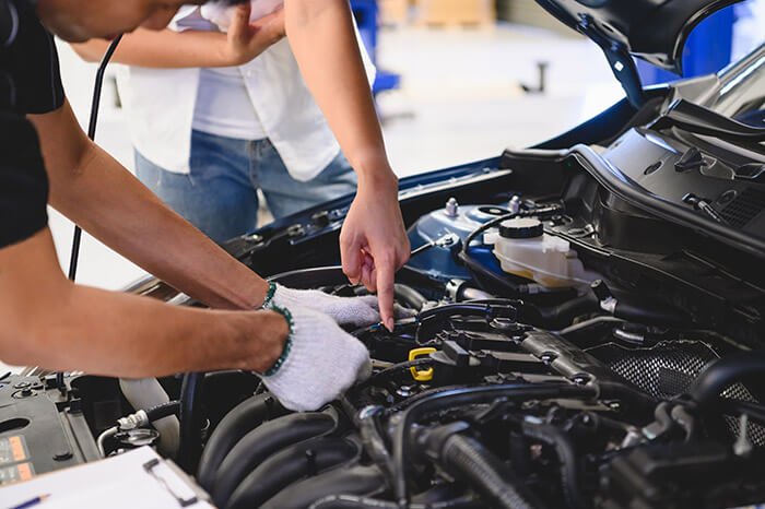 Mécanicien et client examinant ensemble le moteur d’une voiture.